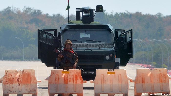 An armed soldier stands in front of a military vehicle in Myanmar