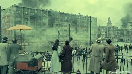 Filmstill aus The Eight Hundred zeigt Menschen, die auf einer Brücke stehen und auf eine Stadt runterschauen, die im Rauch versinkt.
