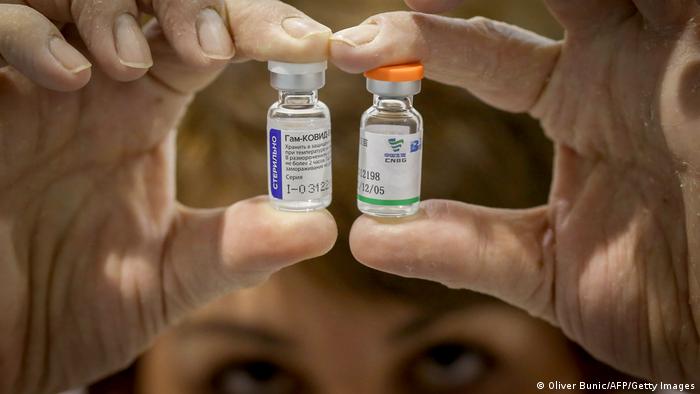 A woman holds up examples of the Russian and Chinese vaccine