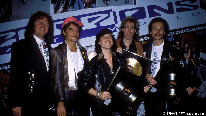 The five band members of The Scorpions holding a golden album award.