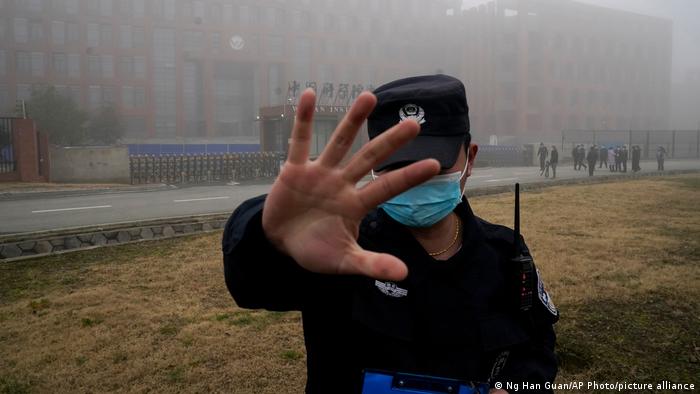 Ein Polizist in Wuhan hält die Hand in die Kamera und trägt eine Maske
