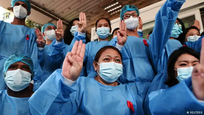 Medical staff in masks protesting with the three-finger salute