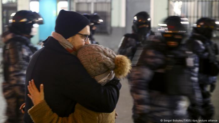 A couple hug as riot police pass