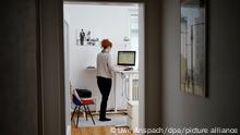 ILLUSTRATION - Eine Frau arbeitet in ihrer Wohnung vor einem Computer an einem Stehtisch.
