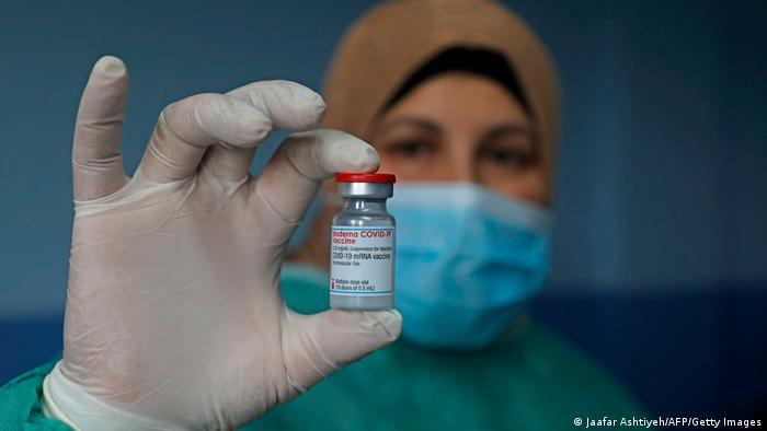 A Palestinian health worker holds a vial of COVID-19 vaccine. 