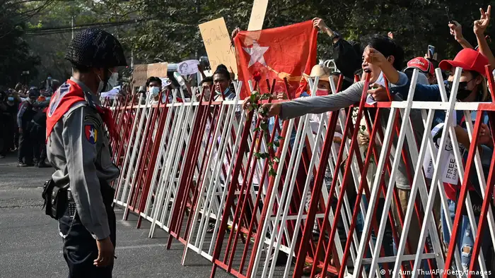 Protester hands a rose to a policeman during a protest in Yangon