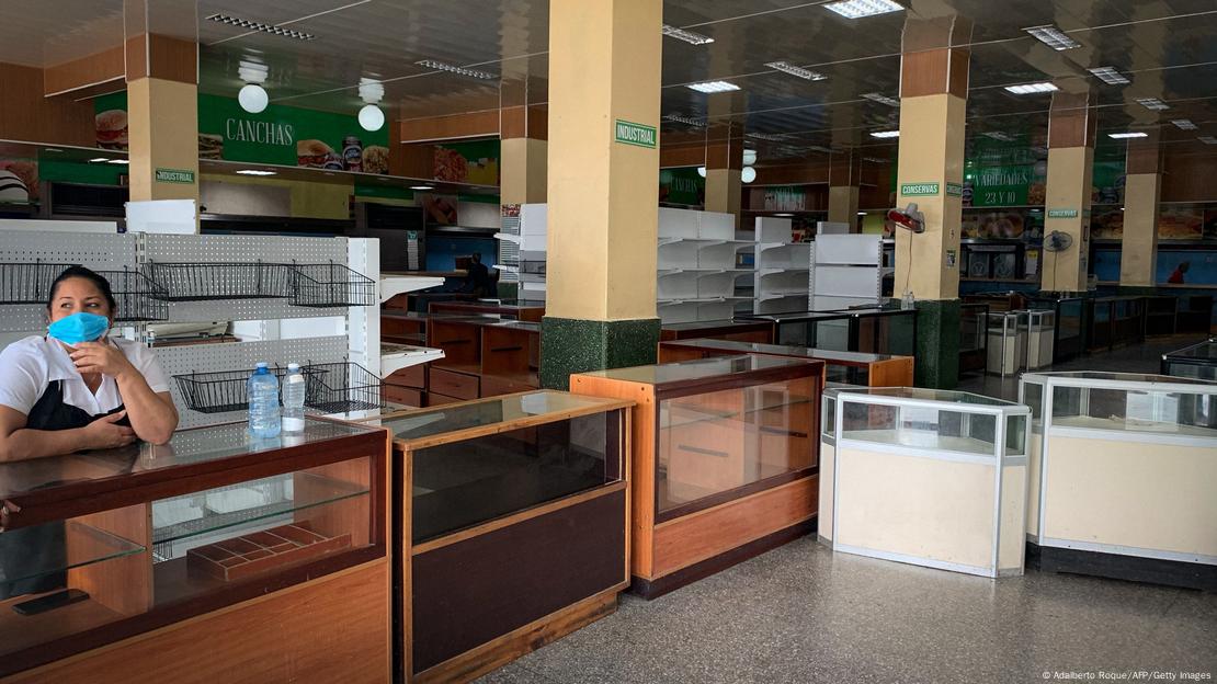 Funcionária solitária em grande mercado com prateleiras vazias em Havana