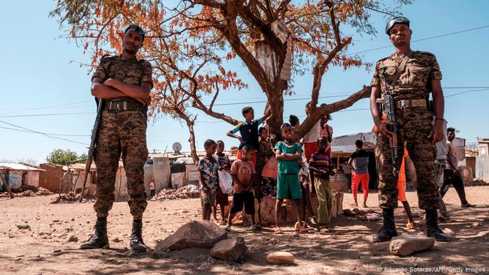 Ethiopian Army soldiers stand as a children stand behind them at Mai Aini Refugee camp, 