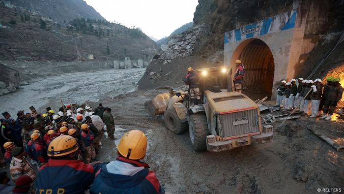 Members of Indo-Tibetan Border Police (ITBP) watch as a machine is used to clear a tunnel after a part of a glacier broke away in India