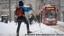Ein Mann mit Langlaufski überquert den Marktplatz. Starke Schneefälle führen zu erheblichen Behinderungen auf Straßen, Schienen und Fußwegen.
