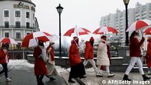 Women wearing clothes with colors of the former white and red flag of Belarus march in the streets under umbrellas to protest against the Belarus presidential election results in Minsk, on December 16, 2020. (Photo by - / AFP) (Photo by -/AFP via Getty Images)