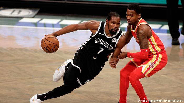 Kevin Durant in the Brooklyn Nets jersey dribbles past an opponent