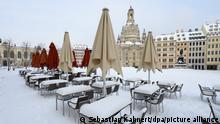 09.02.2021, Dresden - Mit Schnee bedeckt sind leere Tische und Stühle auf dem Neumarkt vor der Frauenkirche. Sachsen will Grundschulen und Kitas vom 15. Februar 2021 an in einem eingeschränkten Betrieb wieder öffnen.