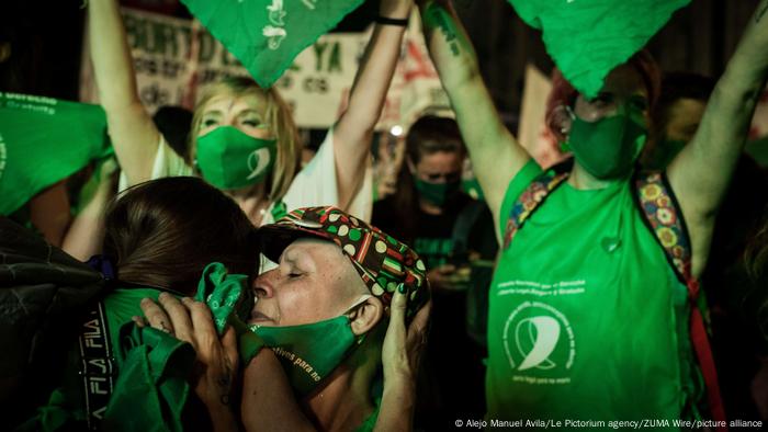 Women wearing green shirts and masks celebrating in Buenos Aires, Argentina. 