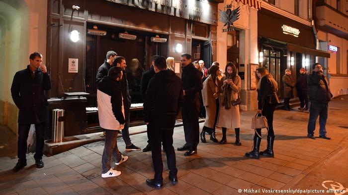 People stand outside restaurants in the center of Moscow