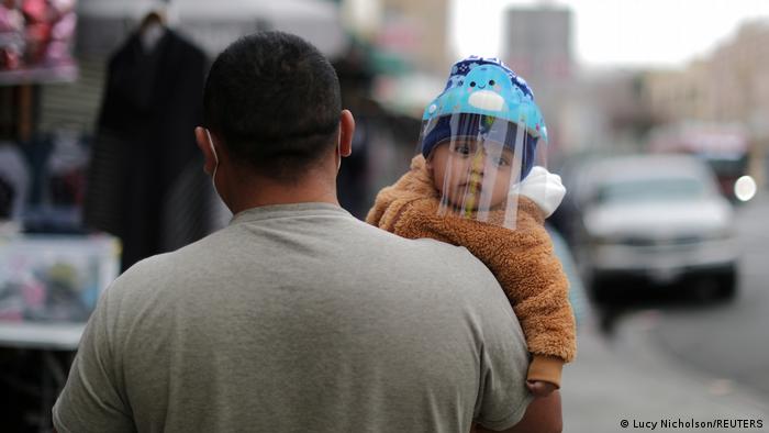 A man carries a baby wearing a mask to protect against COVID-19 in Los Angeles, California, February 10, 2021