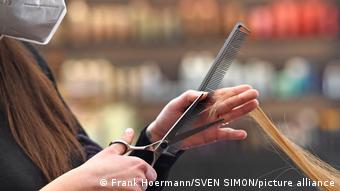Парикмахер стрижет волосы женщине