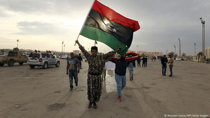 Libyan men in Benghazi wave their national flag during a demonstration marking the fifth anniversary of the Libyan revolution