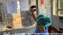 A medical worker checks a person's temperature at the Matanda Hospital in Butembo, where the first case of Ebola died, in the North Kivu province of Congo, Thursday, Feb. 11, 2021. A second case and death of Ebola has been recorded in Congo's North Kivu province after a 60-year-old woman died Wednesday, according to officials. (AP Photo/Al-hadji Kudra Maliro)