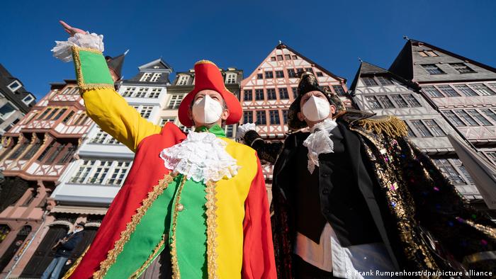 Zwei Verkleidete mit Corona-Schutzmaske vor der Kulisse der Kölner Altstadt