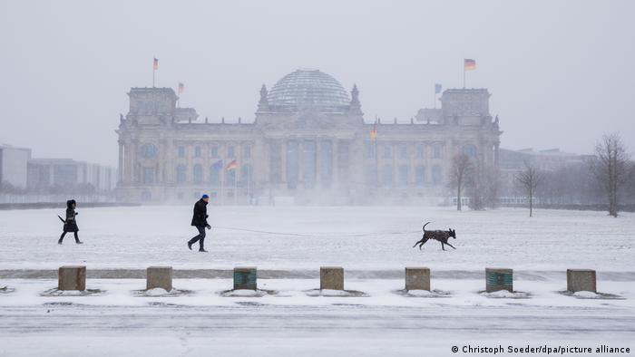 People walking past the Reichstag building in the snow
