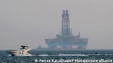 An offshore drilling rig is seen in the waters off Cyprus' coastal city of Limassol, Sunday, July 5, 2020 as a boat passes with a skier. Russian President Vladimir Putin has promised to intercede with Turkey to try and ease rising tensions over its oil and gas exploration in eastern Mediterranean waters that Cyprus claims as its own, the Cypriot government said Thursday, July 30, 2020. (AP Photo/Petros Karadjias)