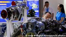 A man takes a closer look at a helicopter engine developed by Motor Sich, Ukraine on display at Aviation Expo China in Beijing, Wednesday, Sept. 20, 2017. A foreign business group is urging China to carry out promises to open its economy and warned inaction might fuel a backlash against free trade amid mounting U.S. and European criticism of Beijing. The European Union Chamber of Commerce in China said Beijing is backtracking in some areas, including imposing new restrictions on good imports, express delivery and legal services. (AP Photo/Andy Wong)