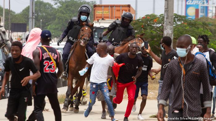 Zwei Polizisten auf Pferden verfolgen weglaufende Demonstranten