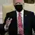 President Joe Biden is seen sitting and wearing a black face mask in the Oval Office 