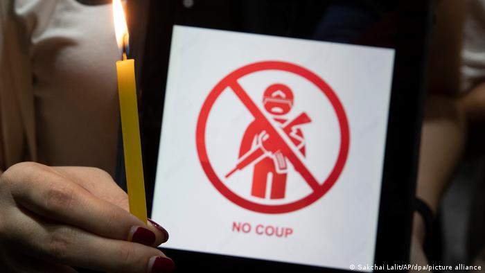 A hand holding a candle and a piece of paper that says no coup.