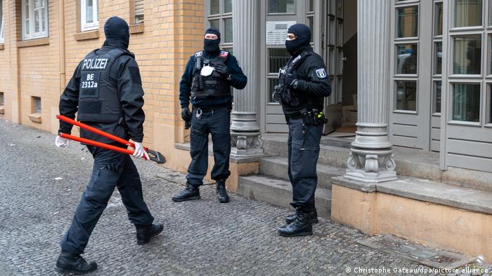 Police in one of the raids, one carrying a pair of bolt cutters
