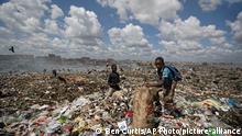 In this photo taken Wednesday, Dec. 5, 2018, Peter, 12, right, scavenges pieces of paper and card from garbage for a living from amongst the garbage at the dump in the Dandora slum of Nairobi, Kenya. As the world meets again to tackle the growing threat of climate change, how the continent tackles the growing solid waste produced by its more than 1.2 billion residents, many of them eager consumers in growing economies, is a major question in the fight against climate change. (AP Photo/Ben Curtis)