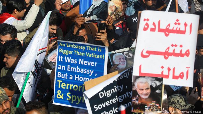 Iraqi demonstrators hold placards at a rally marking one year since the killing of the two commanders in a US drone strike