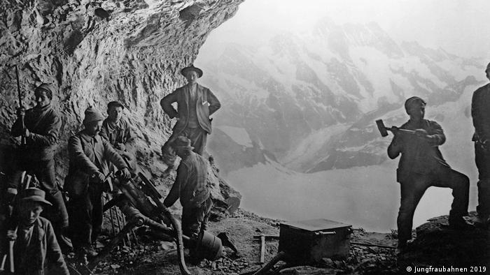 Historical photograph of the construction of the Jungfrau Railway line (black and white): men hammering the tunnel into the rock with tools