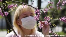 ROSTOV-ON-DON, RUSSIA - MAY 1, 2020: A woman in a face mask looks at blossoms of redbuds in mid-spring during the pandemic of the novel coronavirus disease (COVID-19). Rostov-on-Don Region, including the city of Rostov-on-Don has been on lockdown since 31 March. The government of Rostov-on-Don Region has made face masks compulsory on public transport, at bus stops, in shops and other public places starting from 1 May. Valery Matytsin/TASS