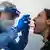 Profissional de saúde faz teste de covid-19 com cotonete em boca de paciente