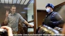 Russian opposition leader Alexei Navalny stands in a cage in the Babuskinsky District Court in Moscow, Russia, Saturday, Feb. 20, 2021. Two trials against Navalny are being held Moscow City Court one considering an appeal against his imprisonment in the embezzlement case and another announcing a verdict in the defamation case. (AP Photo/Alexander Zemlianichenko)