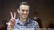 Russian opposition leader Alexei Navalny gestures as he stands in a cage in the Babuskinsky District Court in Moscow, Russia, Saturday, Feb. 20, 2021. Two trials against Navalny will be held: Moscow City Court will consider an appeal against his imprisonment in the embezzlement case and Babushkinsky District Court will announce a verdict in the defamation case. (AP Photo/Alexander Zemlianichenko)