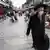 Homem de máscara andando em rua de pedestres