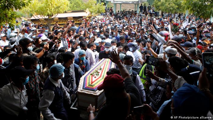 A large group of people carries a coffin