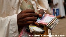 A money exchanger counts money at a popular market, in Khartoum, Sudan, Monday, June 24, 2019. Sudan's protest movement accepted an Ethiopian roadmap for a civilian-led transitional government, a spokesman said on Sunday, after a months-long standoff with the country's military rulers — who did not immediately commit to the plan. (AP Photo/Hussein Malla)