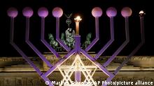 A giant Hanukkah Menorah set up by the Jewish Chabad Educational Center, is illuminated at the Pariser Platz in front of the Brandenburg Gate in Berlin, Tuesday, Dec. 12, 2017. (AP Photo/Markus Schreiber)