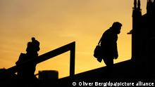 Menschen, die Schutzmasken tragen, gehen im Morgenlicht eine Treppe hinauf. Die sogenannte Sieben-Tage-Inzidenz in Nordrhein-Westfalen ist aktuell auf 61,7 gestiegen. +++ dpa-Bildfunk +++