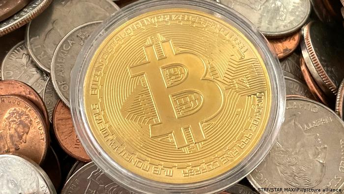 A bitcoin lays atop a pile of US coins