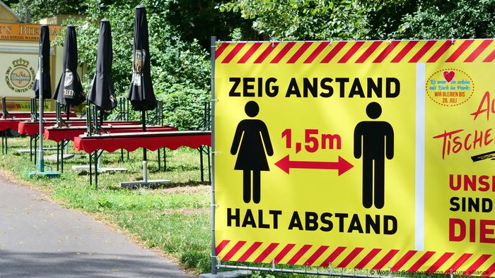 a large yellow sign, a pictogram of two keeping their distance 