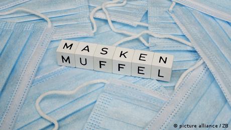 Auf medizinischen Masken ist das Wort Maskenmuffel mit Buchstaben-Würfeln gelegt 