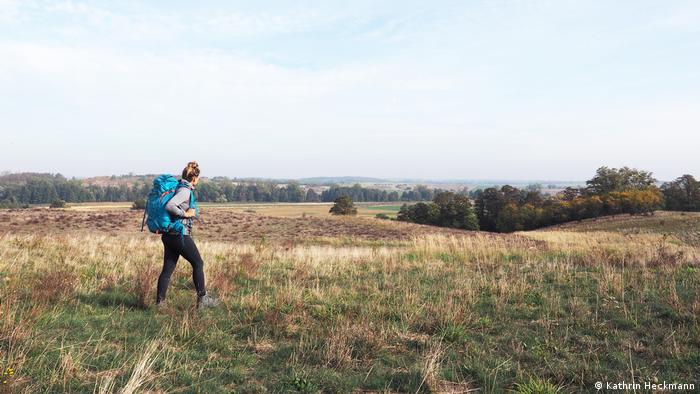 Travel influencer and blog writer Kathrin Heckmann hiking across a field in the Uckermark region, Germany