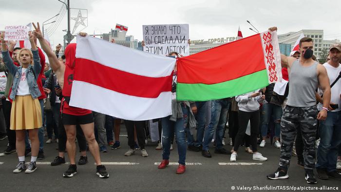People hold the former and the actual flags of Belarus during an opposition rally