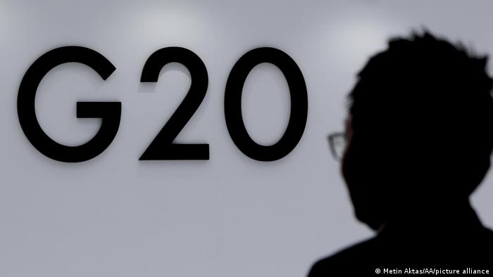 Foto simbólica de una persona que camina frente al logo del G20 en una imagen de archivo.