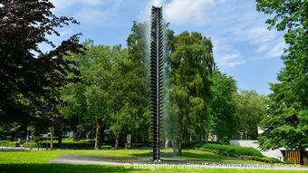 Water flows from a towering sculpture in the middle of a park